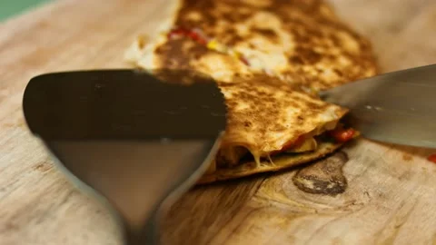 Cutting a freshly fried chicken quesadilla on a wooden cutting board. Process of Stock Footage 151294954