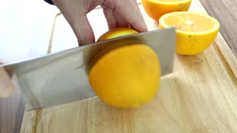 Cutting A Full Orange In Half With A Large Knife Video stock 134175612