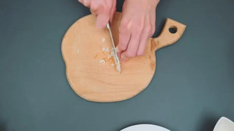 Cutting garlic with a sharp knife on a cutting board Stock Footage 249898477