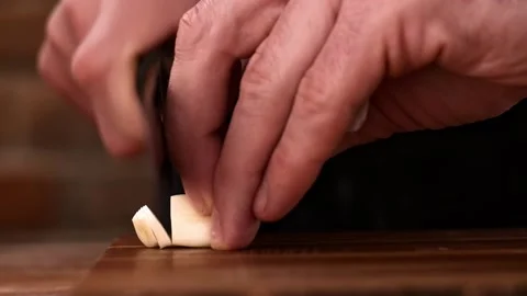 Cutting garlic into small slices with a knife on a wooden board Video stock 149078507