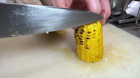 Cutting glazed grilled corn on the cob into pieces with knife, Japan Stock-Footage 345125275