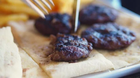 Cutting grill meat on a plate with fork and knife in busy cafe Stock Footage 327112683