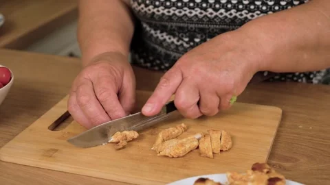 Cutting grilled chicken breast for preparing Caesar salad. Slicing cooked Stock Footage 333241581
