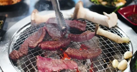 Cutting grilled Hanu beef into smaller pieces with kitchen scissors on a Stock Footage 320517401