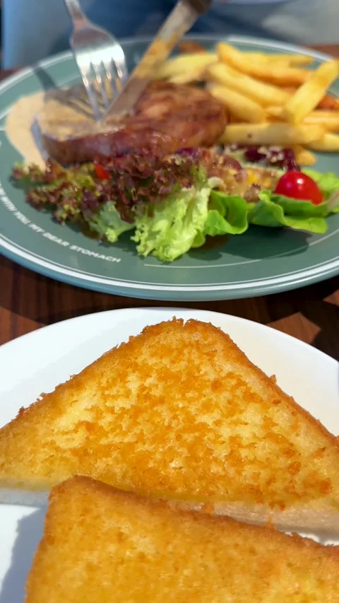 Cutting a Grilled Pork Steak Served with French Fries and Garlic Bread Stock Footage 335734135