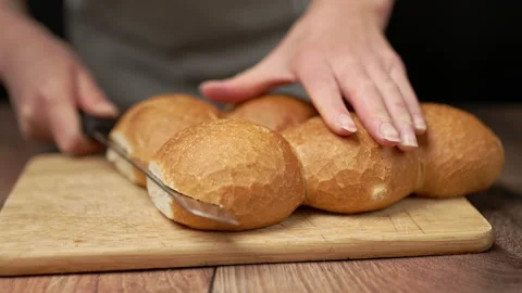 Cutting in half bread rolls with a bread knife in slow motion. Stock Footage 135462576