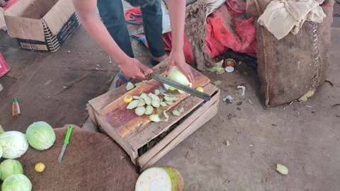 Cutting a jackfruit using a large knife over a wooden platform. Stockbeeldmateriaal 256975768