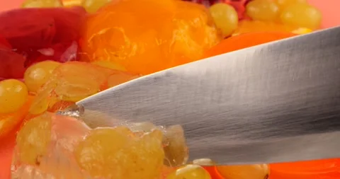 Cutting with a knife blade of a multi-colored berry gelatin jelly  Stock Footage 220126130
