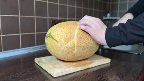Cutting Large Ripe Yellow Melon into Two Halves Stock Footage 315991737