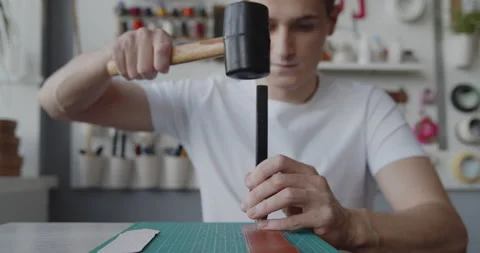 Cutting leather belt with an oblong punch tool and a mallet close-up Stock Footage 144891653