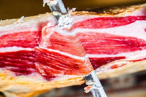 Cutting a leg of 100% Iberian ham with sharp ham knife. Appetizing and delici Stock Photos