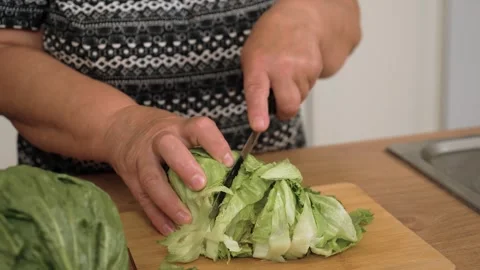 Cutting lettuce leaves for preparing Caesar salad. Slicing fresh greens for Stock Footage 333314058