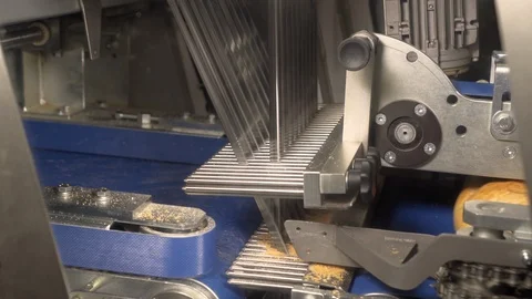 Cutting a loaf of bread into pieces and packing it into bags. Machine for Stock Footage 105619223