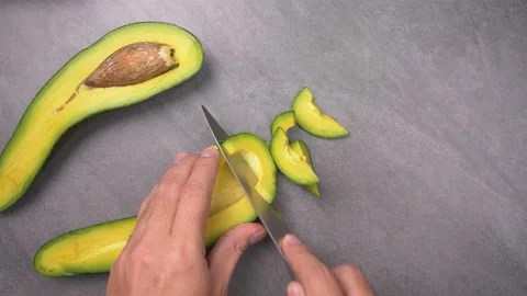 Cutting a long avocado on table. Healthy breakfast and Vegetarian food. Top view Stock Footage 135776527