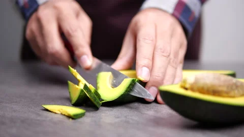 Cutting a long avocado on table. Healthy breakfast and Vegetarian food. Close-up Stock Footage 135777439