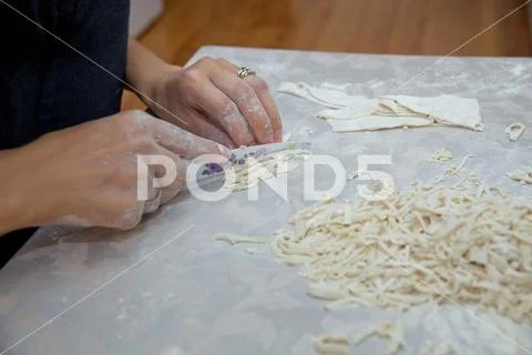 Cutting long dough stripe for cooking pasta. Homemade food preparation concep Stock Photos