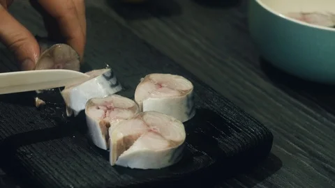 Cutting mackerel into pieces on a black cutting board Stock Footage 100975231