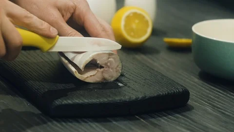 Cutting mackerel into pieces on a black cutting board Stock Footage 100975353