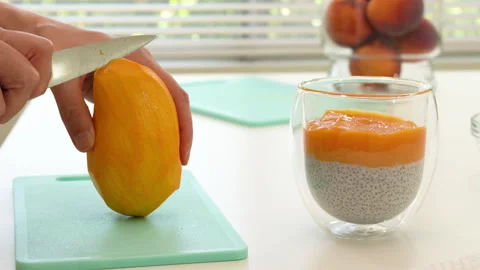 Cutting mango on cutting board. Mango Chia seed layered pudding smoothie step by Stock Footage 147699061