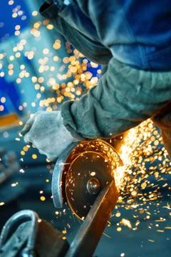 Cutting a metal beam using an angle grinder. A lot of sparks fly out from under Stock Photos
