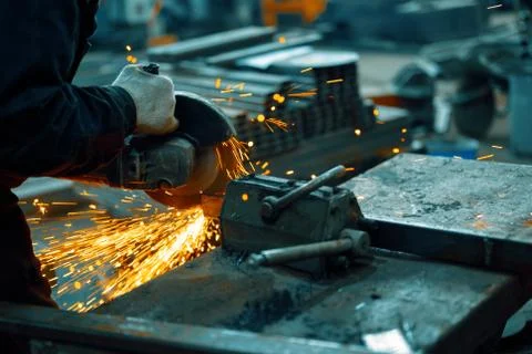 Cutting a metal beam using an angle grinder. A lot of sparks fly out from under Stock Photos