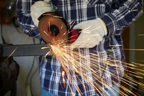 Cutting a metal part with an angle grinder in a workshop 스톡 사진