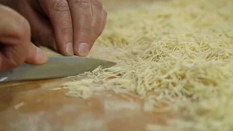 Cutting of noodles roll on cutting board by hands close up Stock Footage 73223468