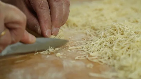 Cutting of noodles roll on cutting board by hands close up Stock Footage 73223485