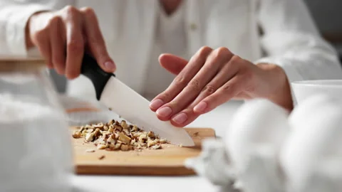 Cutting nuts with a white knife on a bamboo board. The chef uses a large kni Stock Footage 213317802