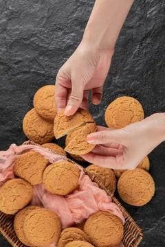 Cutting an oatmeal cookie in the hand into two pieces Stock Photos