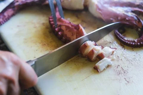 Cutting octopus with knife on kitchen table. Concept of Seafood. Stock Photos