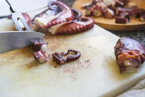 Cutting octopus with knife on kitchen table. Concept of Seafood. Stock Photos