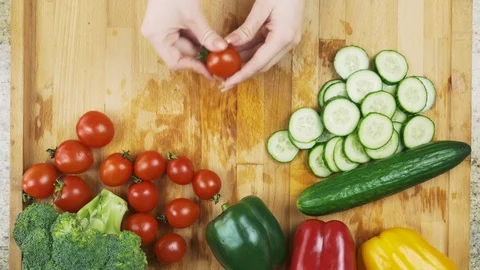 Cutting one red cherry tomatoes with kitchen knife on wooden board Stock Footage 78487717