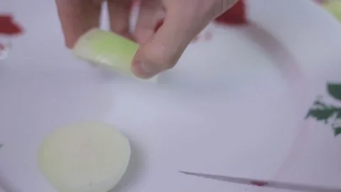 Cutting an onion into chunks and then slicing it on a white plate Stock Footage 75612434