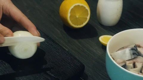 Cutting onions into rings, laying on the fish and squeezing lemon juice. Stock Footage 100975376