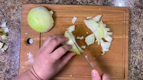 Cutting onions into small cubes with a knife on a wooden cutting board. Top view Stock-Footage 300458402