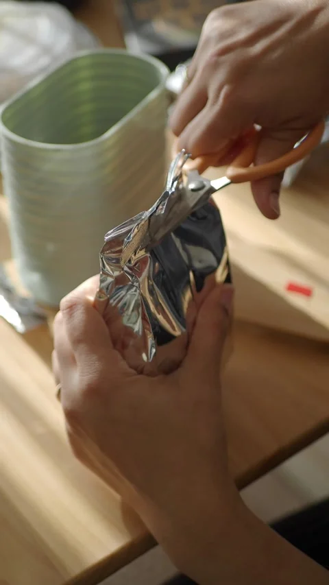 Cutting open a packet with scissors using hands in an indoor setting Video stock 345964615
