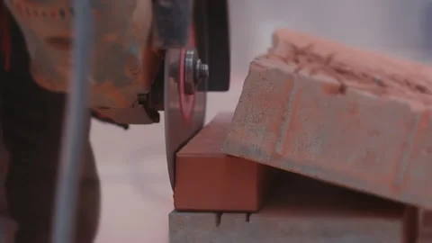 Cutting an orange brick with a circular saw with a grinder during a close-up Stock Footage 291200330
