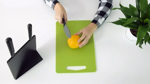 Cutting orange with kitchen knife on green board, white background Stock Footage 102790098