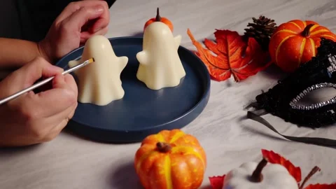 Cutting out Halloween jelly ghosts among festive fall decor with pumpkins and Stock Footage 320067462