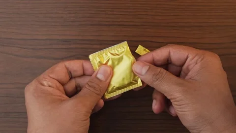 Cutting pack of condom with fingers and showing condom. Stock Footage 328213110