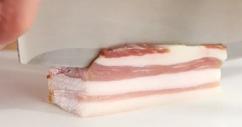 Cutting pancetta with a knife on a cutting board. Ingredient for pasta carbonara Stock Footage 245355332