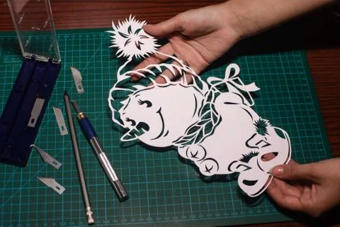 Cutting paper patterns snowing with a knife on a special rug. snowman out of Stock Photos