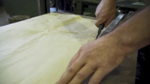 Cutting paper with utility knife using ruler as guide on worktable Stock Footage 314074043