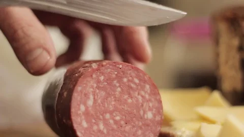 Cutting a piece of sausage. Close-up man hand with knife Stock Footage