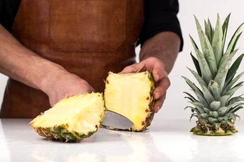 Cutting pineapple on a white surface with the help of knife Stock Photos