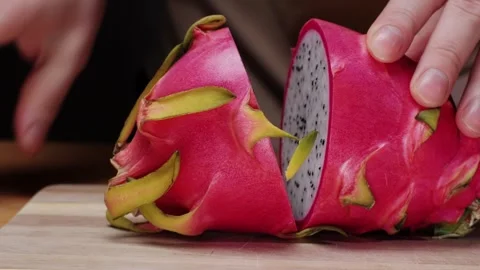 Cutting pink dragon fruit by knife close-up. Exotic Pitaya or pitahaya is a Stock Footage 274749142