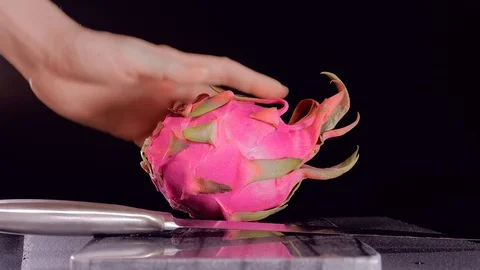 Cutting a Pitahaya (Dragon Fruit) on black background. Видео 121708404