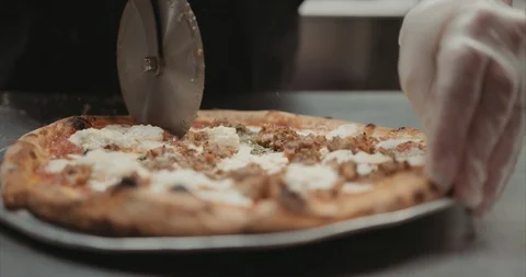Cutting pizza after it was cooked in a brick oven Stock-Footage 105313096