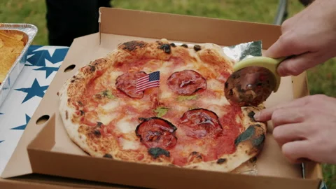 Cutting Pizza into Pieces with tiny American Flag in the middle Video stock 133612061